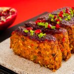 Photo of sliced vegan rolls served. Vegetarian roll made of lentils and vegetables and garnished with forest fruit jam, pomegranate and celery.