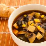 Photo of a tasty Chinese soup with veggies, fresh ginger, nori, tofu and mushrooms. A vegan recipe.