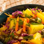 Photo of a colorful potato salad with carrot, spring onions, purple cabbage, corn, caper and delicious mustard sauce.