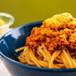 Photo of a bowl of spaghetti, with Βolognese sauce made by vegetables and minced soy. A vegan recipe from All About Vegans.