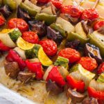Photo of grilled vegetables skewers (souvlakia) with mushrooms, green and red peppers, cherry tomatoes and zucchini. A vegetarian and vegan recipe from All About Vegans.