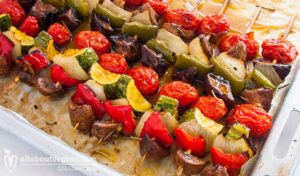 Photo of grilled vegetables skewers (souvlakia) with mushrooms, green and red peppers, cherry tomatoes and zucchini. A vegetarian and vegan recipe from All About Vegans.