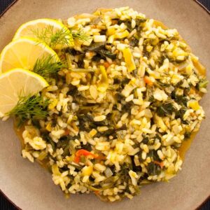 Photo of a plate with spinach with rice, leeks and tomato. A vegan & vegetarian version of the traditional Greek spanakorizo recipe.