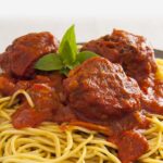 Photo of a dish with pasta with vegan lentil no-meatballs in tomato sauce with basil from All About Vegans.
