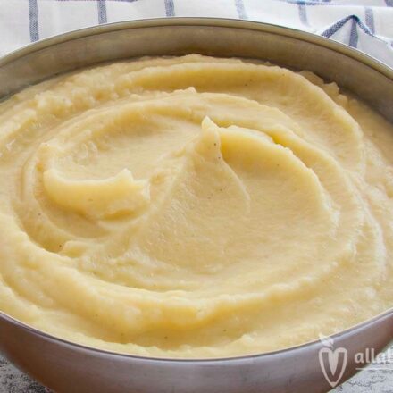 Photo of a bowl of mashed potatoes. Next to it there is a wooden spoon, a towel and nutmeg. A vegan recipe from All About Vegans.