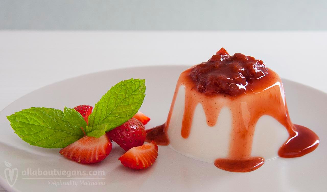 Photo of vegan panna cotta with strawberry sauce, served with strawberries and mint leaves