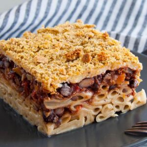 Photo of a piece of pastitso with minced black beans in red sauce and béchamel made of almond milk. A vegan, therefore vegetarian, recipe from All About vegans.