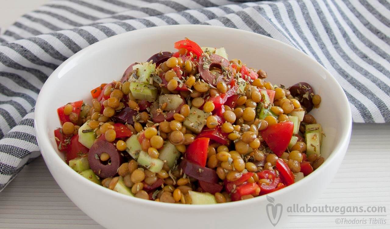 Photo of a bowl with a salad of lentils, olives, cherry tomatoes, oregano and balsamic sauce. A vegan recipe from All About Vegans.