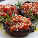 Φωτογραφία γεμιστά μανιτάρια πορτομπέλο με ντομάτα, δεντρολίβανο και φυτικό τυρί σε λευκό πιάτο. Μια βίγκαν και χορτοφαγική συνταγή από το All About Vegans.