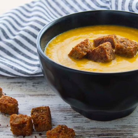 Photo of a bowl of pumpkin soup served with freshly toasted croutons. A vegan recipe from All About vegans.