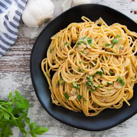 Photo of spaghetti pasta with garlic and olive oil (Aglio e olio) and sprinkled with fresh parsley. A vegan and vegetarian recipe from All About Vegans.