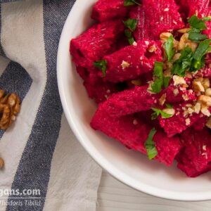 Φωτογραφία ενός πιάτου με κόκκινα/φούξια μακαρόνια. Πέστο παντζαριών γαρνιρισμένα με μαϊντανό και καρύδια. Μία vegan συνταγή από το All About Vegans.